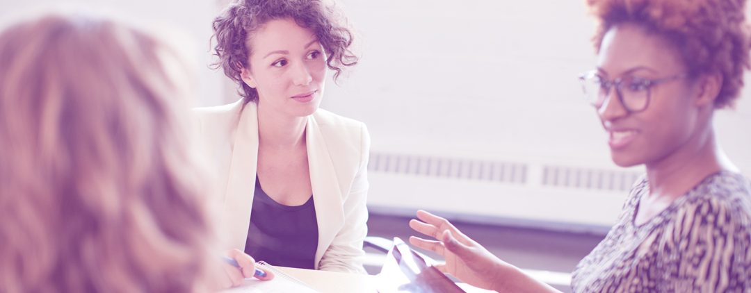 An image of three women sat round a table at a business meeting